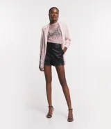 Short negro de cuero sintético con cintura alta, cierre frontal con botón y cremallera, y pinzas en la parte trasera.