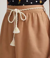 Short ancho color marrón claro, confeccionado en algodón, viscosa, modal y lino. Presenta pliegues y cordón trenzado en la cintura.