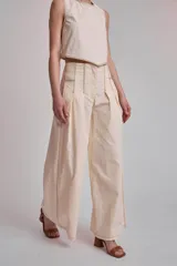 Conjunto color crema compuesto por top corto sin mangas y pantalón palazzo de tiro alto con pinzas y pespuntes a contraste.