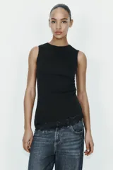 Camiseta ajustada (slim fit) de cuello redondo y manga sisa, color beige claro, con frunces laterales y bajo asimétrico con terminación de encaje a tono.