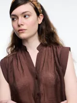 Camisa negra sin mangas con cuello mao y cierre frontal con botones.