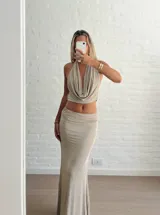 Conjunto color beige compuesto por un top halter con escote drapeado y una falda larga ajustada.