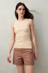 Musculosa blanca de punto canalé fino, sin mangas y con lazos ajustables en los laterales.