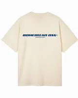 Remera de algodón color beige claro, corte oversize y manga corta. Presenta un estampado en la espalda con el texto "BOHEMIAN DSG®" en azul y debajo "CERTIFIED AUTHENTIC STREETWEAR" en letras más pequeñas.