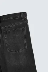 Bermuda de denim de algodón, color gris claro lavado, de corte ancho (baggy fit) y largo hasta la rodilla. Presenta cinco bolsillos y cierre frontal con cremallera y botón.