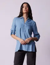 Blusa celeste en lyocell, con cuello a la base con solapa, escote en V y abertura central con botones. Manga larga regulable con presilla y botón.