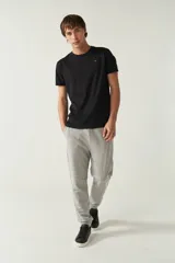 Pantalón de jogging negro de felpa con puños y cintura ajustable con cordón. Presenta logo de goma en la pierna izquierda y bolsillos laterales.