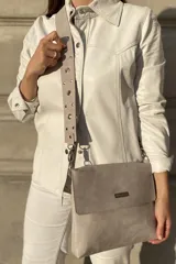 Bandolera de cuero color gris con correa extensible con tachas y arandelas. Tiene forro y bolsillo interno con cierre. La solapa tiene un imán para cerrar con mayor seguridad.