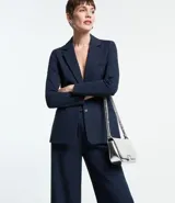 Blazer femenino de corte alargado, color gris oscuro, con cuello solapa, cierre frontal de dos botones y bolsillos incorporados.