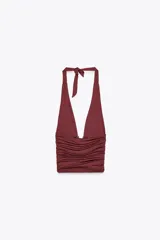 Top negro de cuello halter ajustable con lazadas, espalda descubierta, detalle de aplicación metálica en el delantero y drapeado lateral.