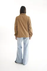 Camisa de pana color borgoña, de corte oversize, con cuello clásico, cierre frontal con botones, dos bolsillos con solapa en el pecho y mangas largas con puños abotonados.