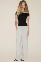 Pantalón palazzo color verde oliva de tejido fluido, tiro medio, cintura elástica ajustable con cordones y bolsillos laterales.