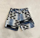 Bermuda de denim con estampado de círculos concéntricos en tonos azul, gris y blanco.