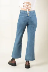 Pantalón de jean azul claro, corte bootcut, con bolsillos delanteros y traseros, y aberturas laterales en el ruedo.