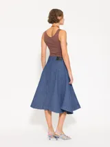 Pollera larga de denim azul con textura en relieve y desgastes, corte acampanado y calce a la cintura.
