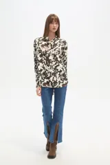 Camisa holgada de manga larga, color negro, con cuello camisa y botones frontales. Presenta apliques de tachas plateadas en los hombros y a lo largo de la tapeta frontal.