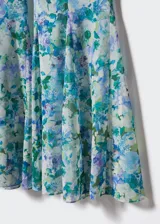 Pantalón acampanado de tejido fluido con estampado floral en tonos azules y verdes, tiro alto y cierre lateral de cremallera.