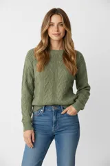 Sweater de punto acrílico color crema, con diseño de trenzas en el cuerpo y mangas, cuello redondo y calce holgado.