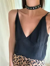 Gargantilla tipo choker de cuero sintético negro, con apliques de estrellas y remaches plateados. Se cierra con cadena y mosquetón para ajustar el largo.