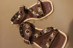 Sandalias bajas color marrón con tiras de cuero y apliques de piedras doradas y marrones.