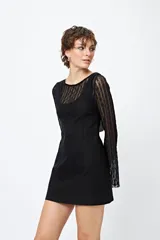 Vestido mini negro de líneas limpias y escote redondeado, con mangas largas de encaje.