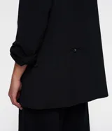 Blazer oversize negro confeccionado en crepé con forro de algodón y viscosa. Presenta hombreras, cuello con solapa y cierre de botón, dos bolsillos de solapa, bordado a mano en la espalda, un falso bolsillo de ribete en la espalda y dos aberturas en la espalda.