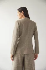 Chaqueta corta color beige, entallada, con escote en V, manga larga y cierre frontal con lazo fijo. Confeccionada en lana fina sin teñir, con bolsillos escondidos y terminaciones enviadas. Hecha 100% en Uruguay.