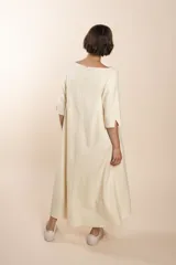 Vestido largo debajo de la rodilla, acampanado, color marrón, con cuello bote, bolsillos laterales y mangas 3/4 con detalle de tajo.