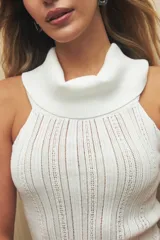 Top tejido de punto color beige, con cuello alto y diseño sin mangas.