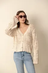 Cardigan color crema tejido al crochet con diseño calado, escote en V y cierre frontal con botones.