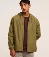 Campera rompevientos color verde oliva, con capucha ajustable con cordón, cierre frontal con cremallera, bolsillos laterales con cierre y puños elásticos.