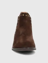 Botín de cuero color marrón oscuro con acabado de gamuza, diseño estilo Chelsea con paneles elásticos laterales y detalles de tachas doradas. Posee punta redonda, taco bajo de 3 cm y forro de algodón orgánico.