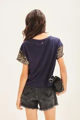 Remera de jersey 100% algodón color blanco, con cuello redondo y manga corta caída. Las mangas están completamente bordadas con lentejuelas tono sobre tono.