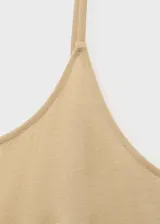 Mono largo color beige, de tirantes finos y corte recto. Incluye cinturón ancho de cuero marrón con hebilla plateada.