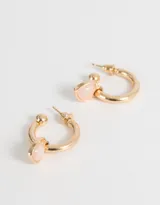 Aros dorados tipo argolla con dije colgante de corazón marrón y moño dorado.