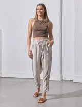 Pantalón de lino color beige con rayas verticales grises, corte recto, cintura alta con cordón ajustable y bolsillos laterales.