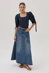 Falda larga de jean celeste con corte evasé, tiro medio y detalles bordados en el frente.