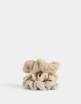 Set de tres scrunchies de pelo en tonos beige, con diferentes texturas: una de piel sintética, una de tela lisa y una tejida.