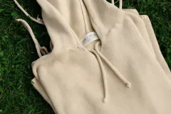 Sweater tejido artesanalmente en hilo 100% algodón color beige, de corte amplio, con capucha y detalles ajustables en mangas y laterales.