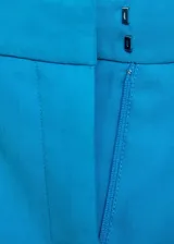 Pantalón de vestir color crema, de corte recto, con cierre de botón y cremallera, tiro medio y bolsillos laterales.