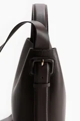 Cartera bandolera de cuero sintético color marrón oscuro, con asa corta superior y correa larga ajustable. Tiene dos compartimentos con cierre magnético y forro interior.