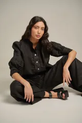 Pantalón negro de lino, de tiro alto y pierna ancha, con pinzas delanteras y cintura marcada.