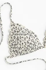 Top de bikini triangular con estampado floral en blanco y negro, ribete festoneado, tirantes finos y copas con relleno push-up.