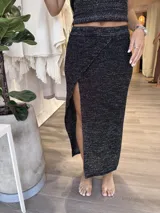 Pollera midi de tejido de punto color negro con lurex plateado, corte recto y abertura lateral.