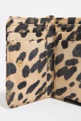 Monedero Bimba y Lola con estampado animal print, confeccionado en nylon con detalles en piel. Cuenta con cierre de cremallera, tirador de piel y cordón, logo metálico y tarjetero interior.