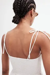 Vestido midi blanco con cuerpo entallado fruncido, escote redondo y breteles spaghetti. Costura fruncida en la cintura y pollera con leve vuelo.