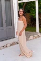 Conjunto de dos piezas color beige claro, compuesto por un top strapless con bajo asimétrico y un pantalón ancho de tiro alto.