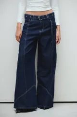 Jean de corte ancho confeccionado en denim azul oscuro con pespuntes a contratono y cinturón desmontable con ojalillos metálicos.
