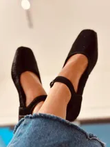 Zapatos tipo Mary Jane color negro, confeccionados en cuero, con punta cuadrada, tira con hebilla sobre el empeine y taco bajo.