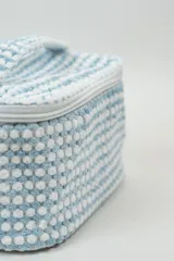 Neceser rectangular con cierre de cremallera, confeccionado en tejido de toalla con textura de motitas en color blanco y rosa pastel.